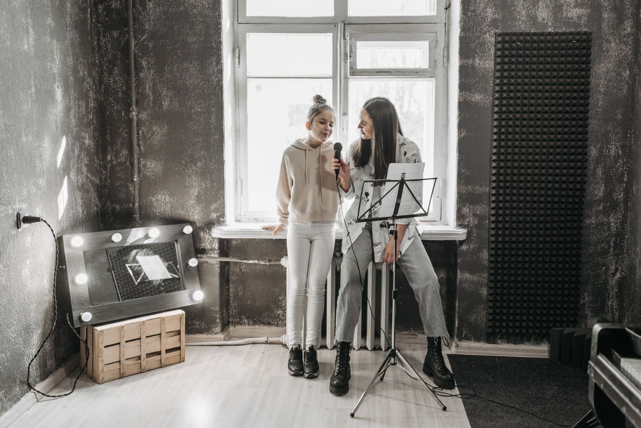 A teenager and teacher singing in a modern studio, enhancing vocal skills.